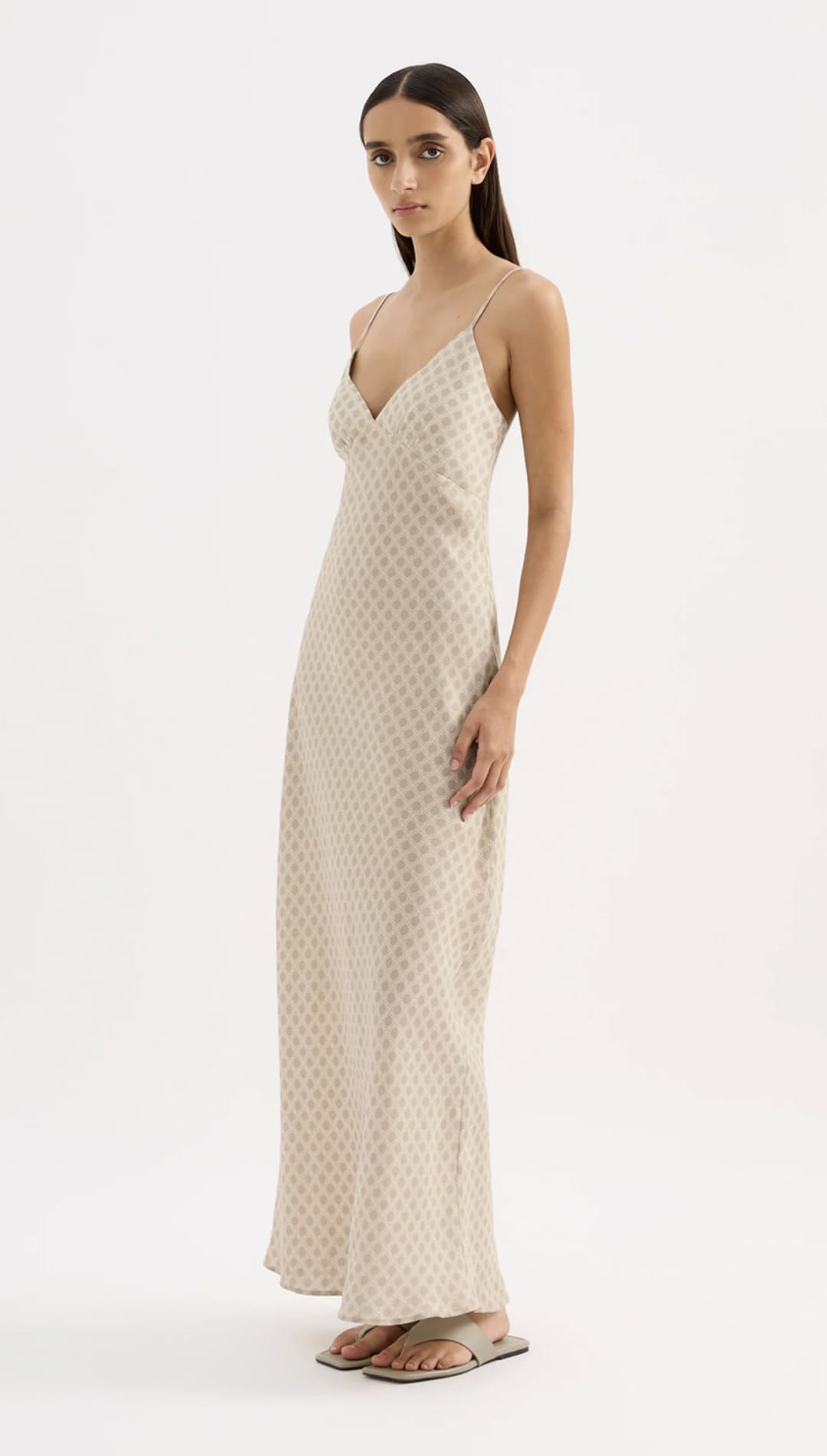 A flowing, off-white slip dress with a subtle geometric pattern and delicate spaghetti straps.