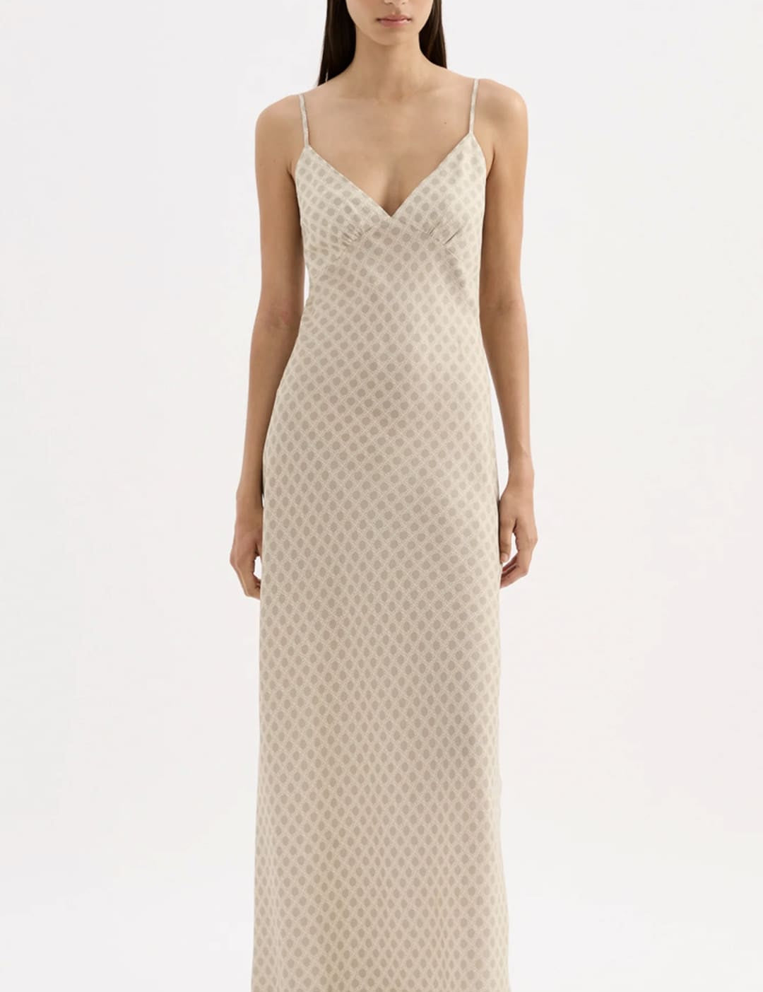 A flowing, off-white silk slip dress with a subtle geometric pattern and delicate spaghetti straps.