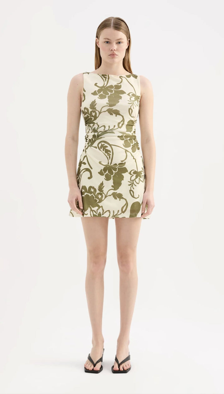 A sleeveless, knee-length dress in cream with an olive green floral pattern.