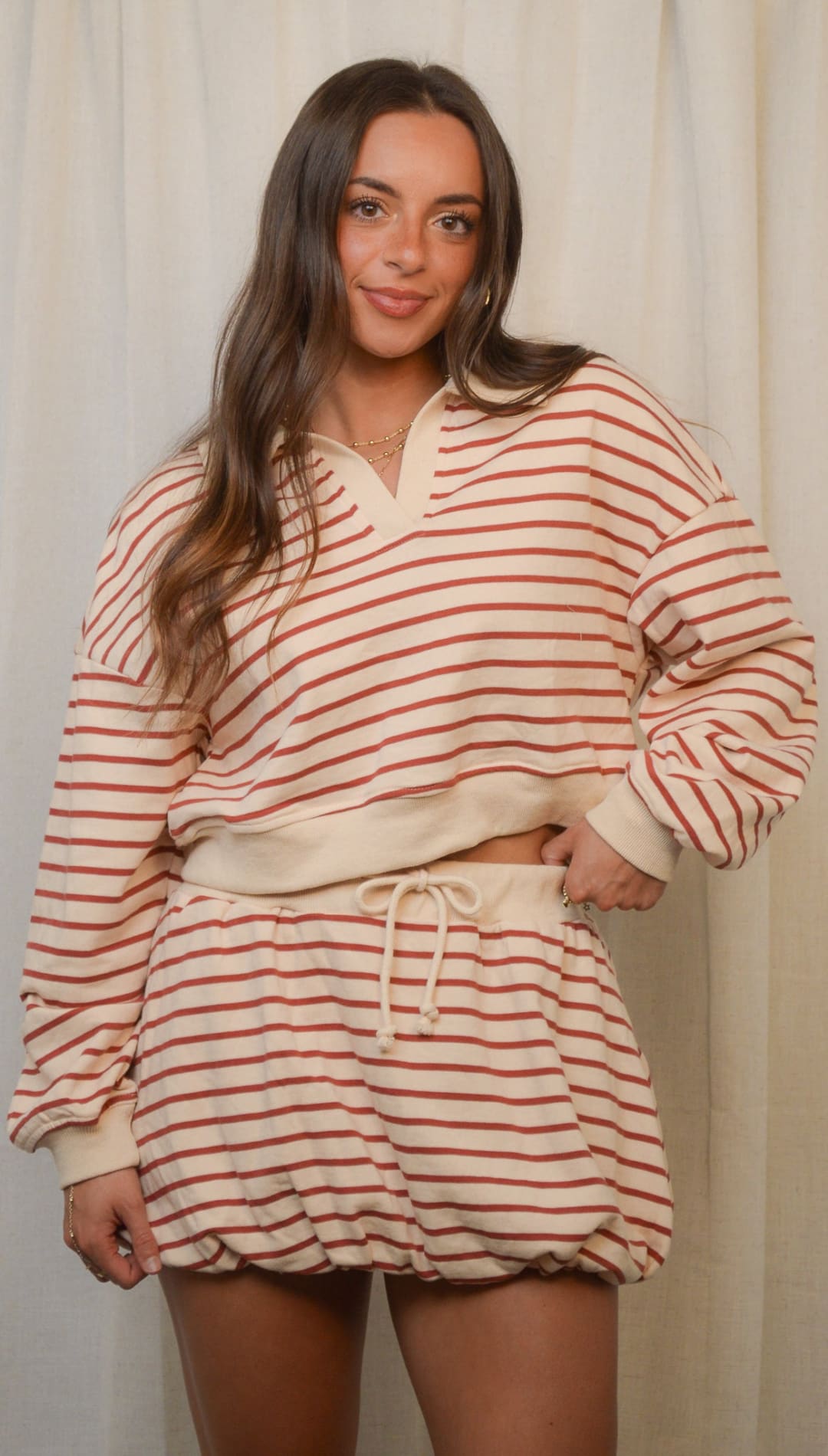 A woman wearing a cream-colored, striped long-sleeve top and matching shorts.