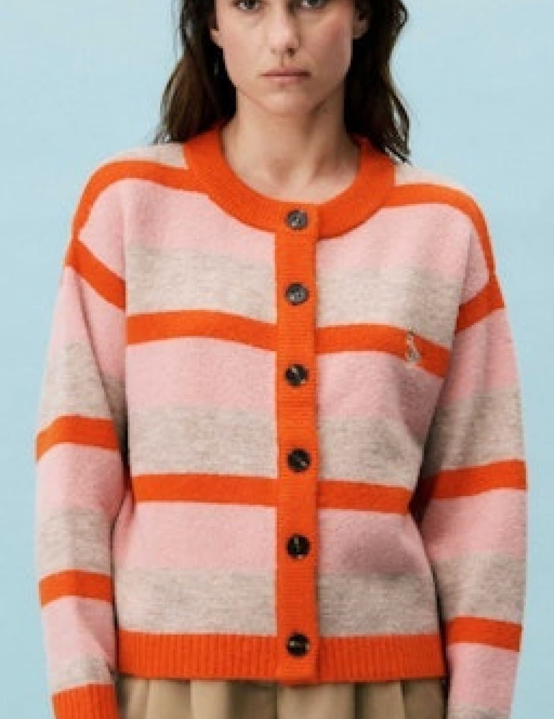 A cozy, long-sleeved cardigan with bold horizontal stripes in soft pink and vibrant orange, featuring a round neckline, button closure, and ribbed cuffs.