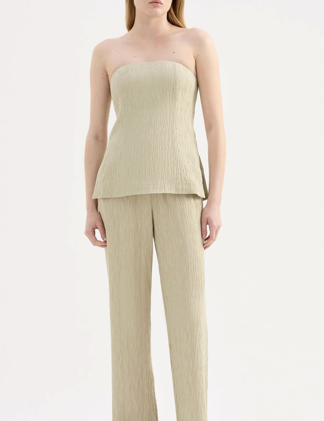 A minimalist beige ribbed knit strapless top with a peplum hem and matching wide-leg trousers.
