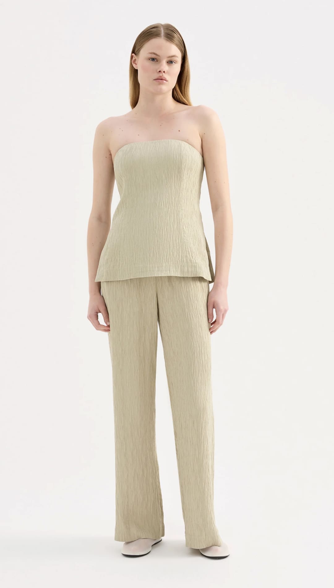 A minimalist beige ribbed knit strapless top with a peplum hem and matching wide-leg trousers.