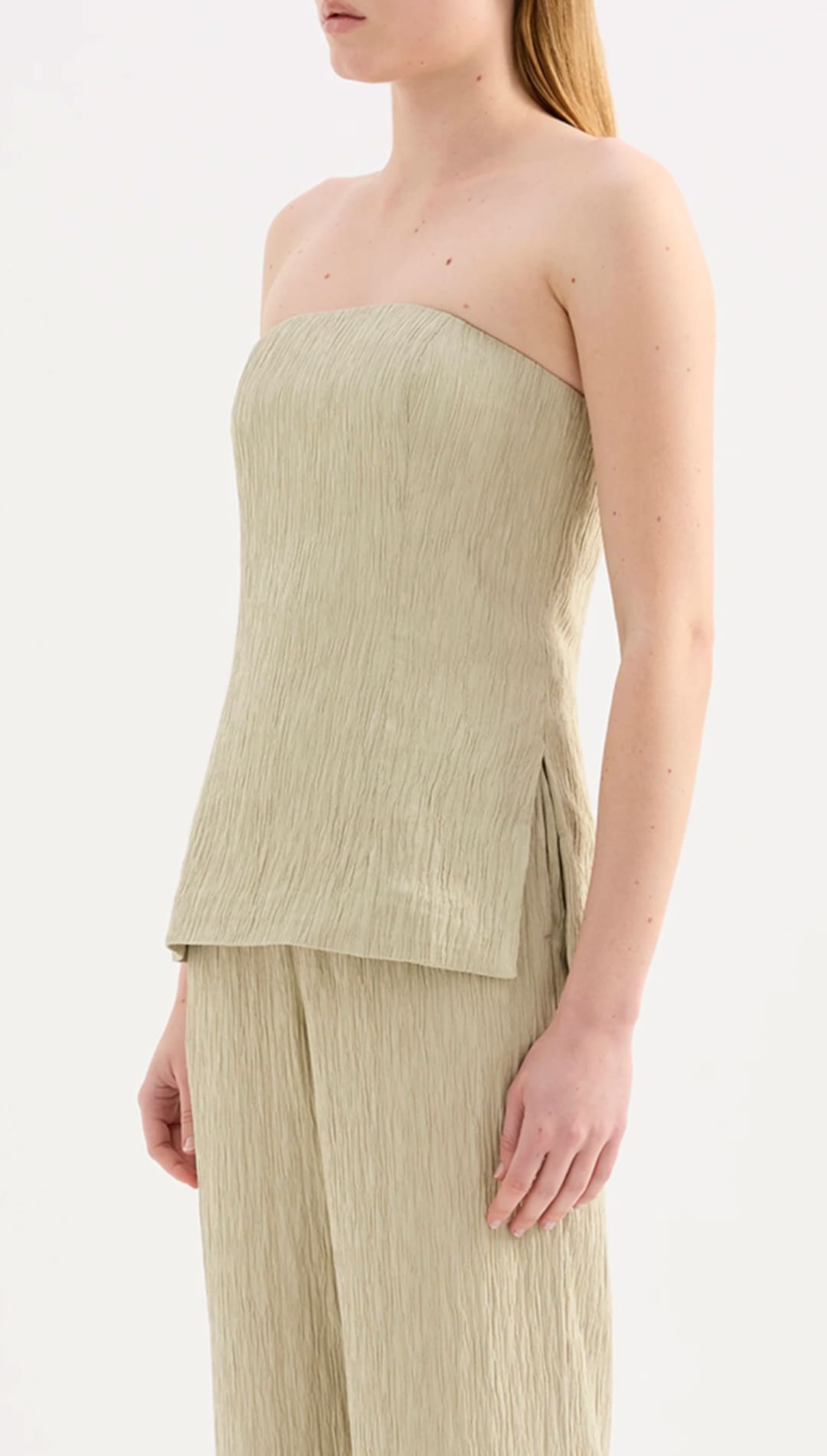 A minimalist strapless top in a soft olive green hue, crafted from textured fabric with subtle vertical pleats and a clean, tailored silhouette.