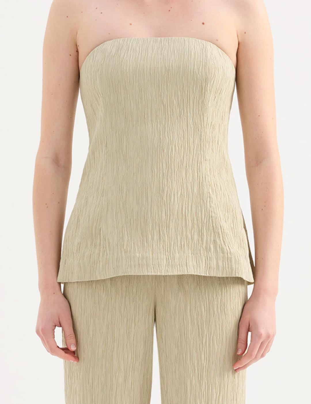 A strapless, light beige top with a textured, pleated fabric that flares slightly at the hem.