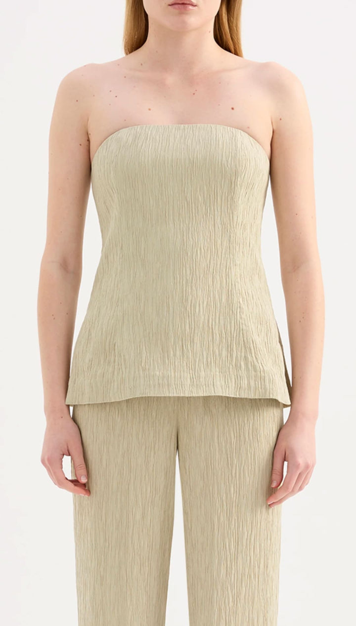 A strapless, light beige top with a textured, pleated fabric that flares slightly at the hem.
