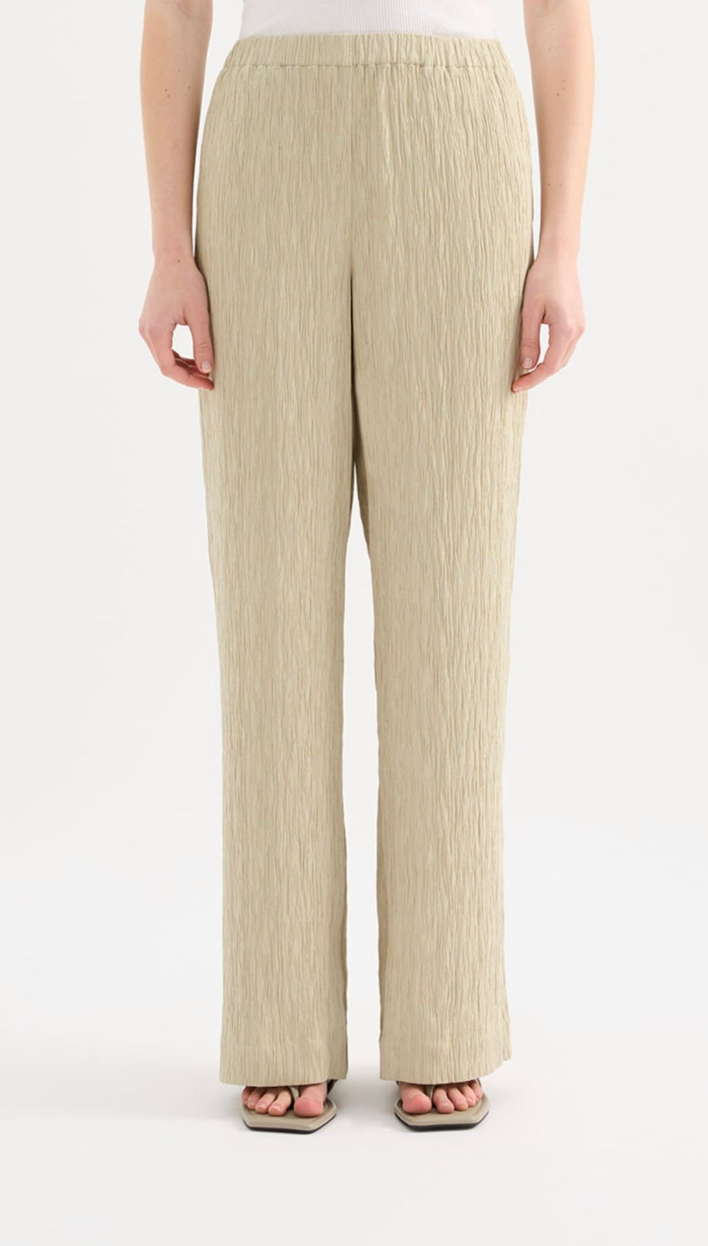 Beige pleated wide-leg trousers with a soft, flowing fabric and an elastic waistband.