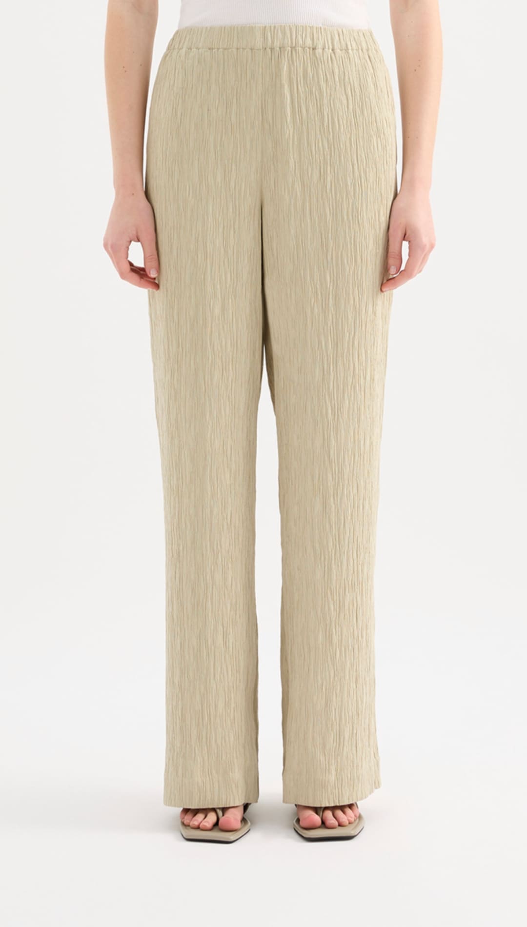Beige pleated wide-leg trousers with a soft, flowing fabric and an elastic waistband.