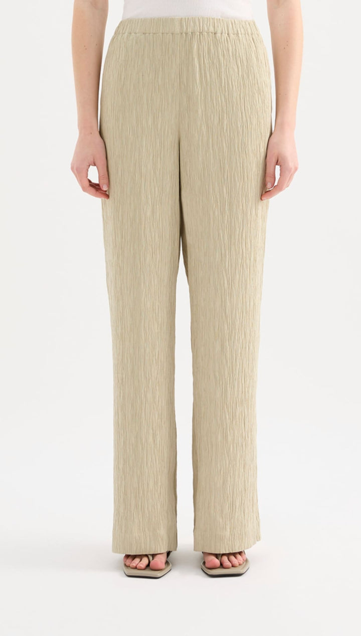 Beige pleated wide-leg trousers with a soft, flowing fabric and an elastic waistband.