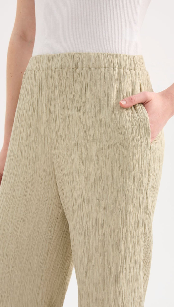 Beige pleated wide-leg trousers with an elastic waistband.