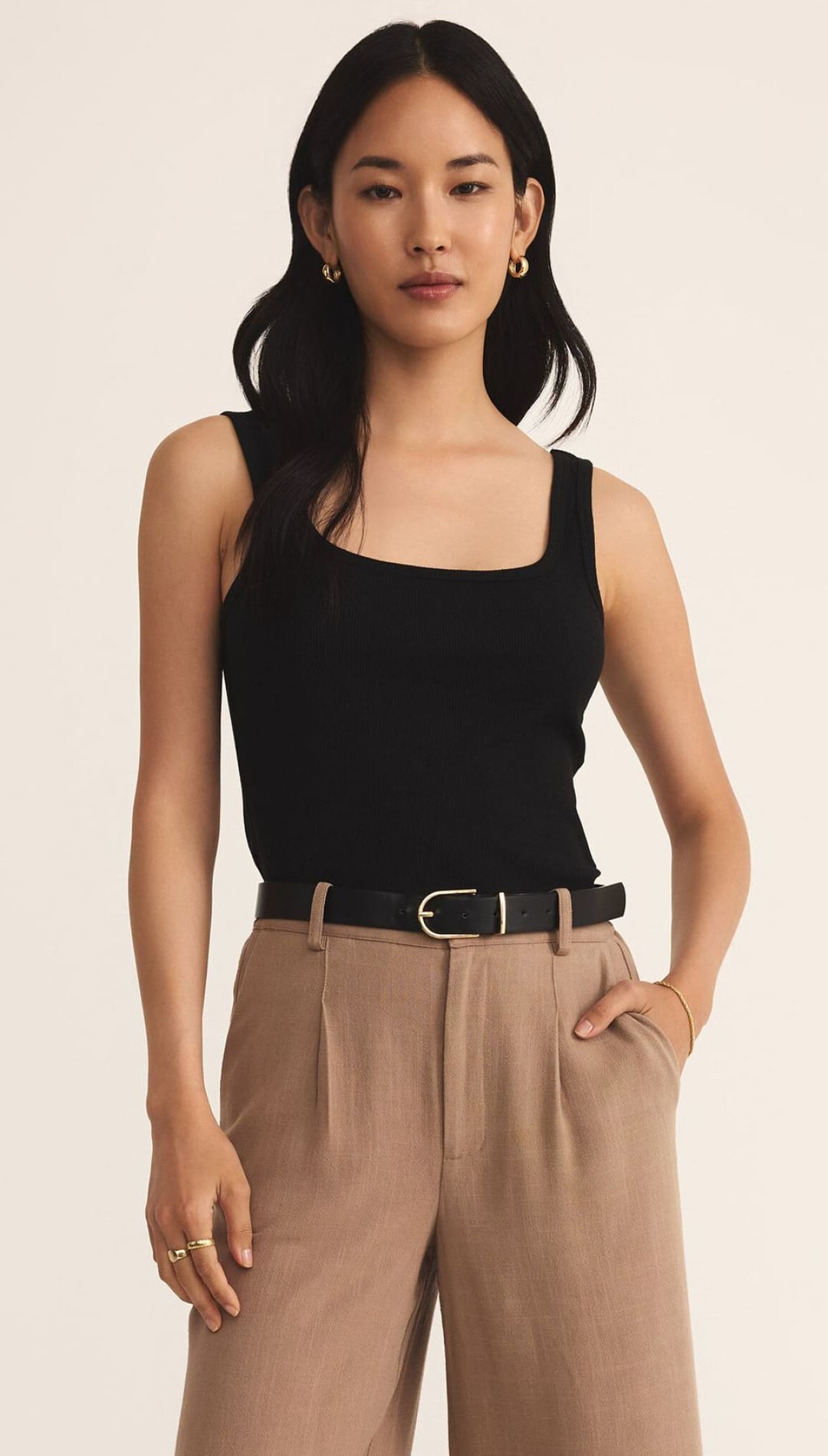 Woman’s black tank top and tan pants.