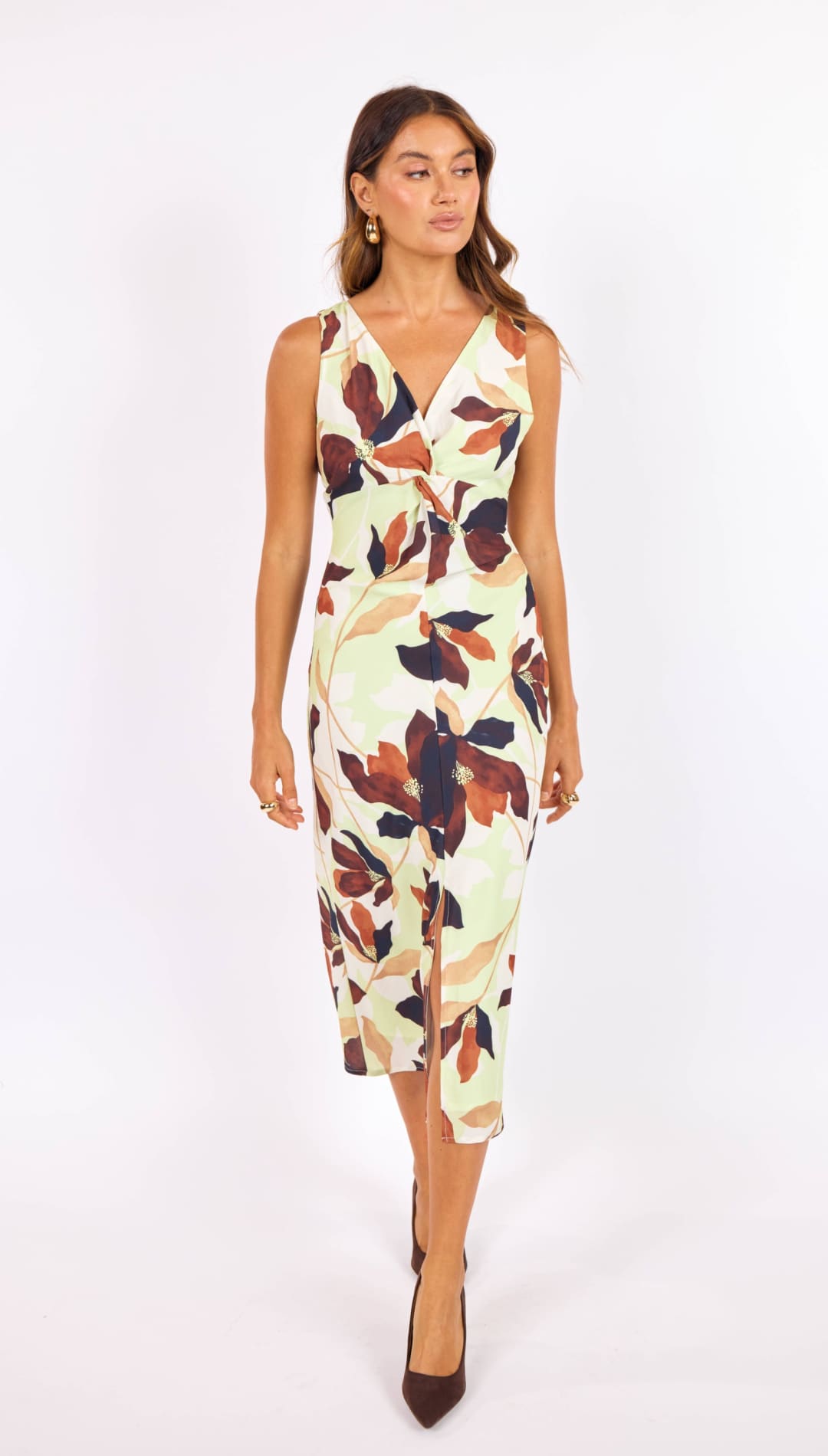 A sleeveless, knee-length dress with a v-neckline and side slit, featuring an elegant leaf pattern in shades of brown, rust, and dark green on a pale cream background.