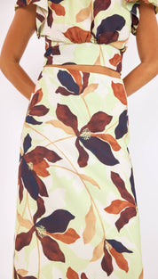 A flowing, light green midi skirt adorned with a bold floral pattern in shades of rust and deep navy.