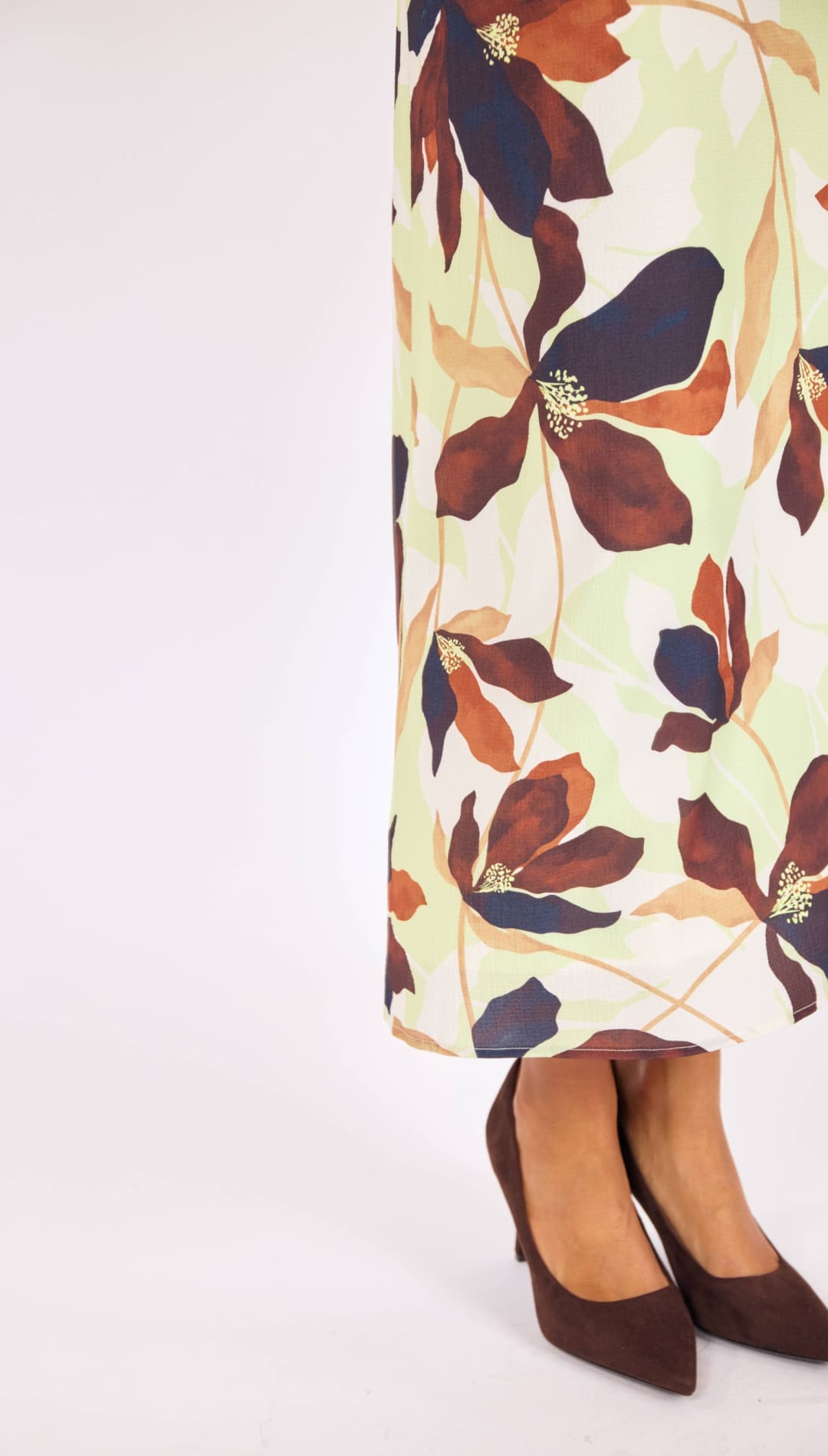 A flowing midi skirt in a cream base with bold floral patterns of deep brown, burnt orange, and navy blue petals accented by gold centers.