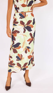 A flowing midi skirt in a light green base fabric, adorned with large floral patterns in shades of brown and navy blue.