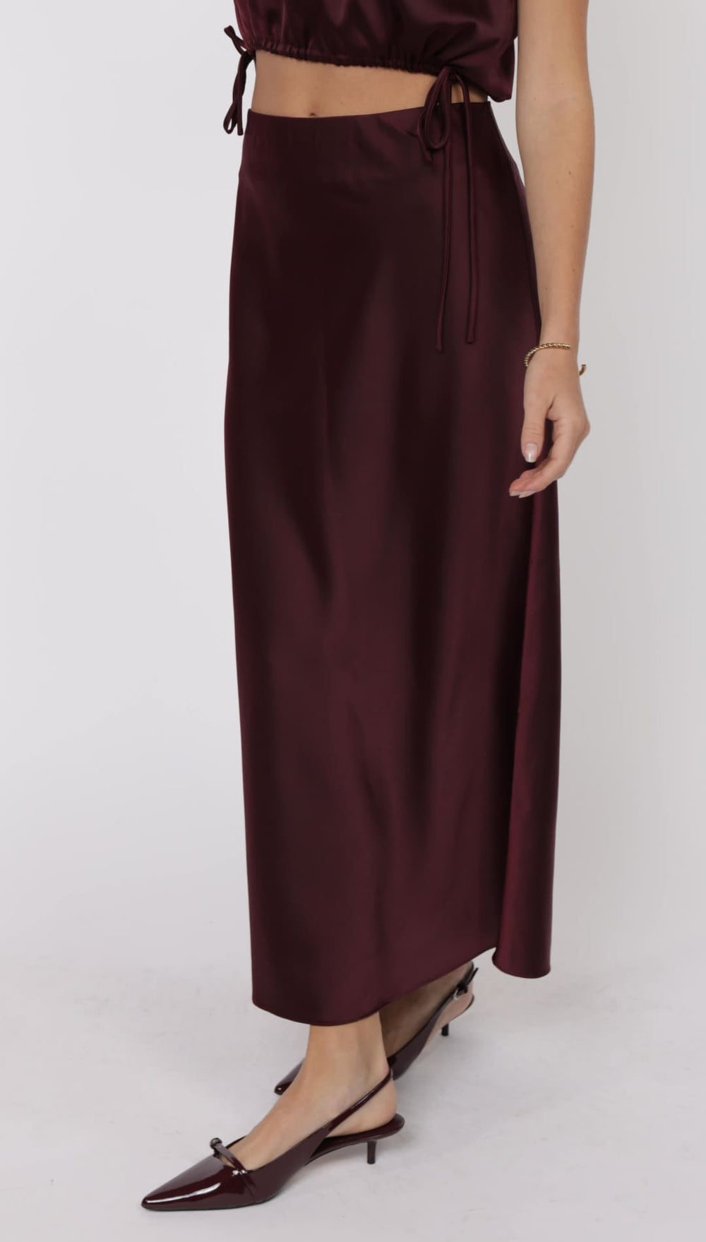 A long, dark plum-colored satin skirt with a side tie detail.
