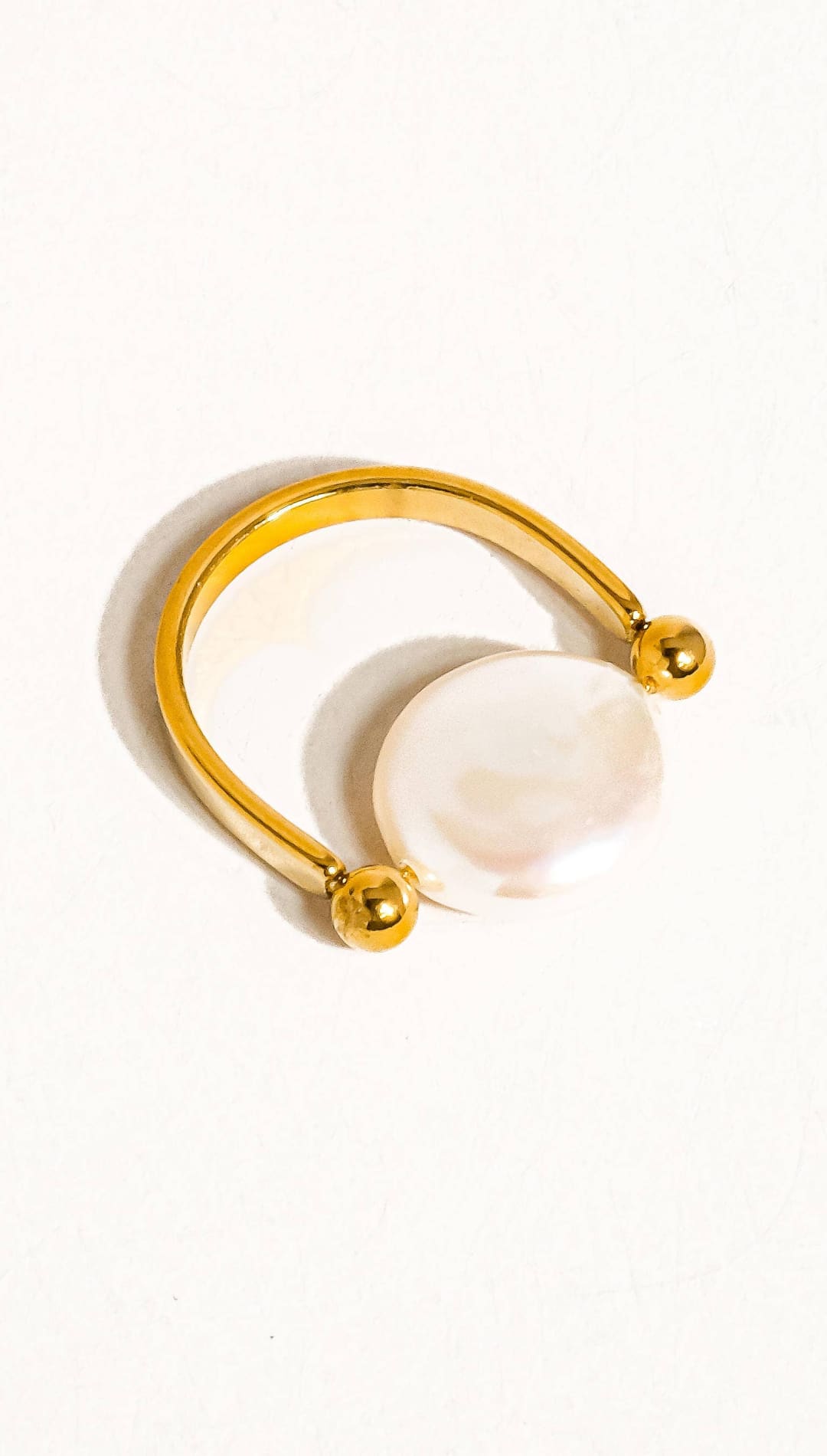 Gold-toned ring with a smooth, round white pearl centered on an open band design.