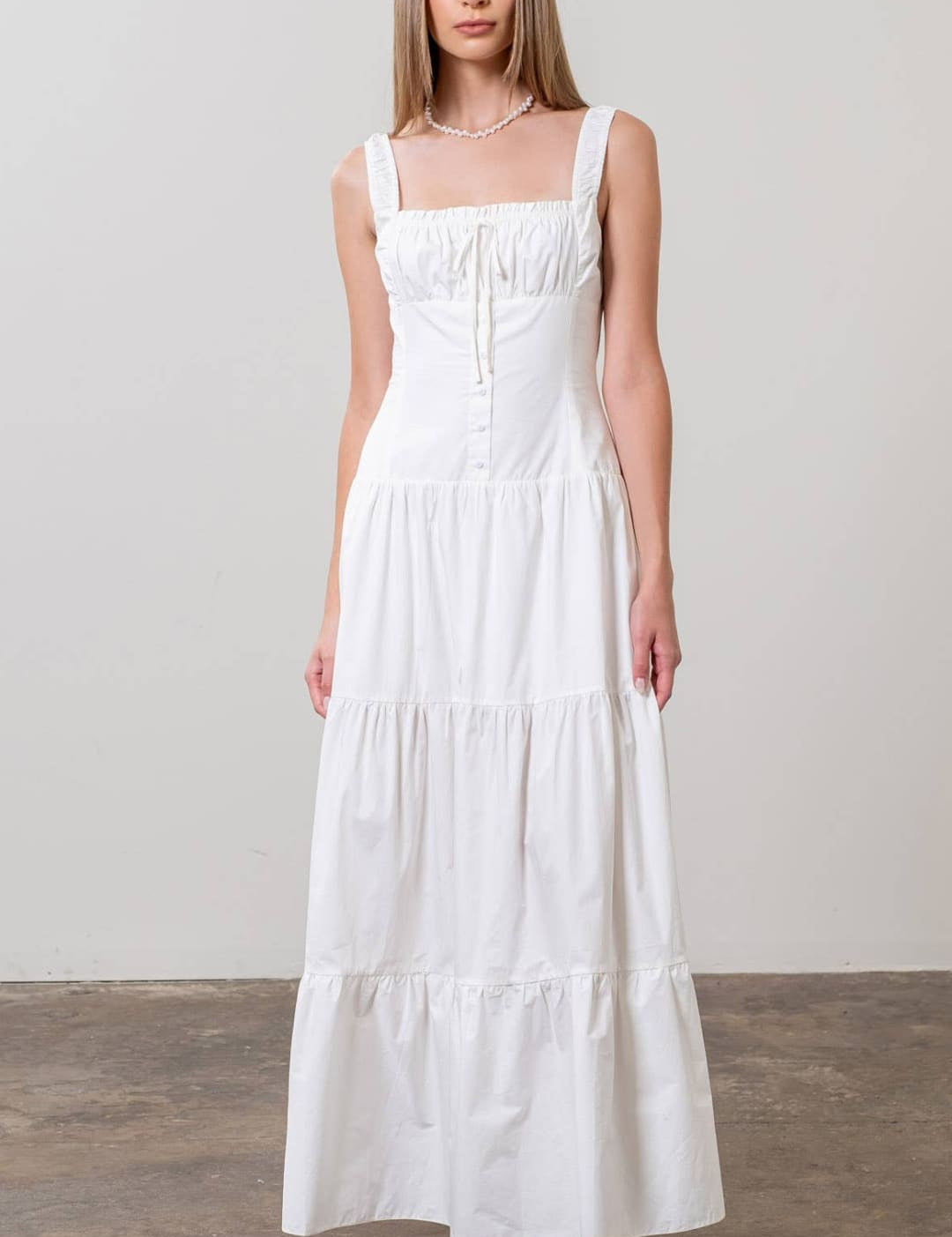 A white tiered maxi dress with thin straps and a square neckline.