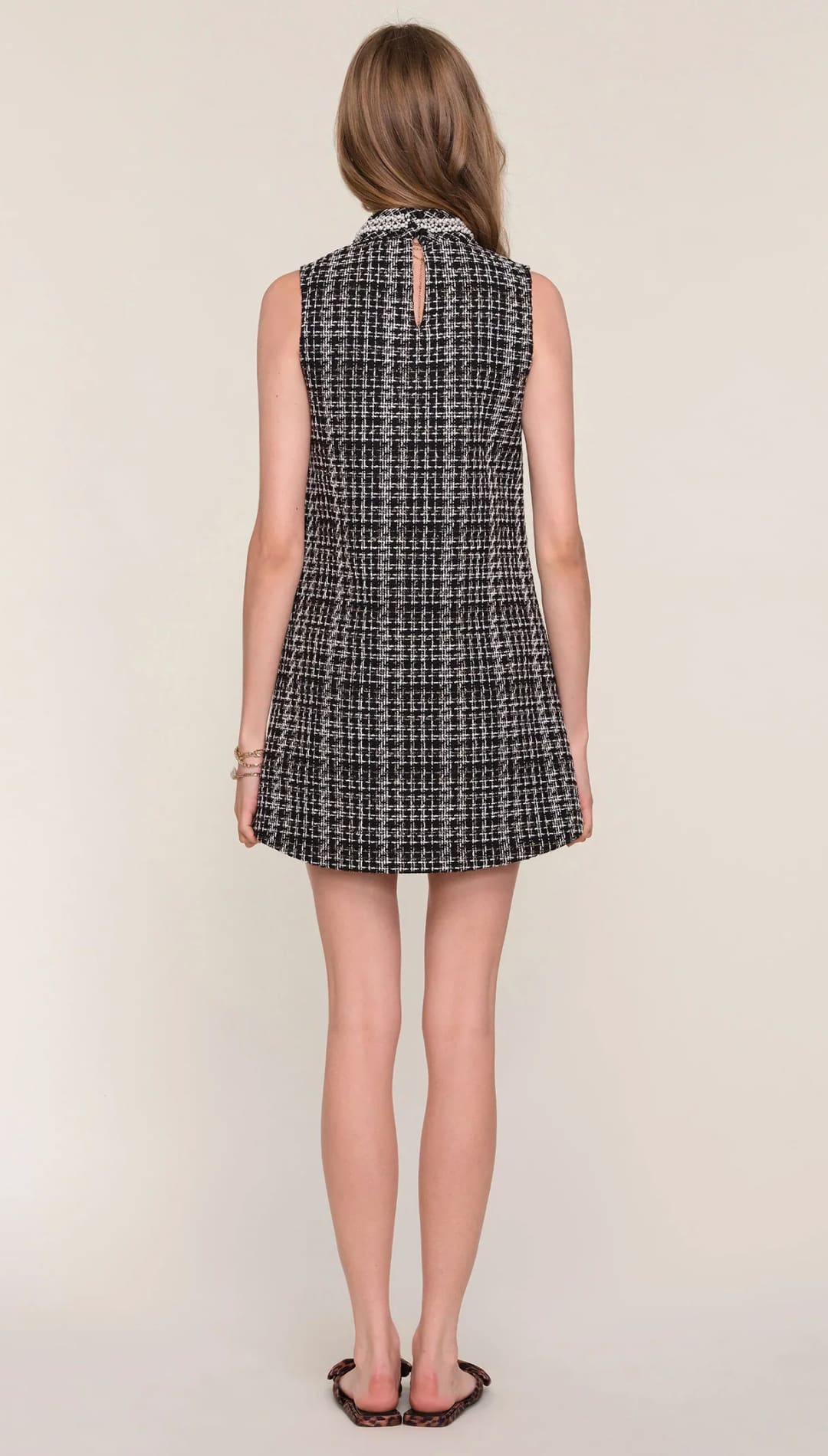 Tweed sleeveless mini dress with a plaid pattern and button detail at the back.