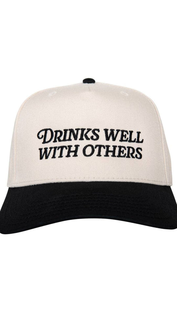White and black trucker hat with ’drinks well with others’ text.