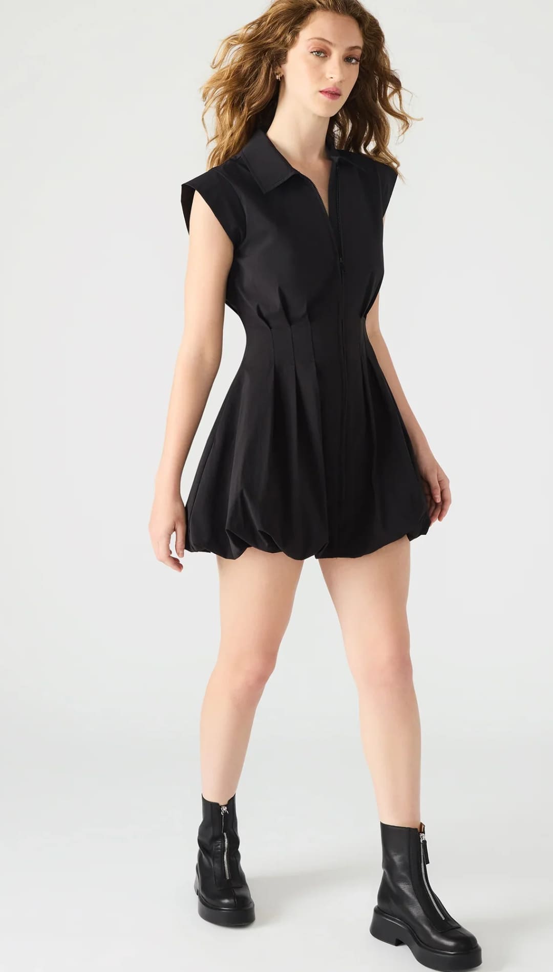 A black collared sleeveless mini dress with a fitted waist and a voluminous bubble hem, paired with black combat boots.