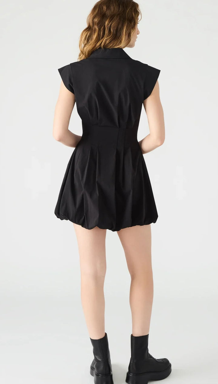 A woman in a black mini dress with a puffed skirt and short sleeves, paired with black platform boots.