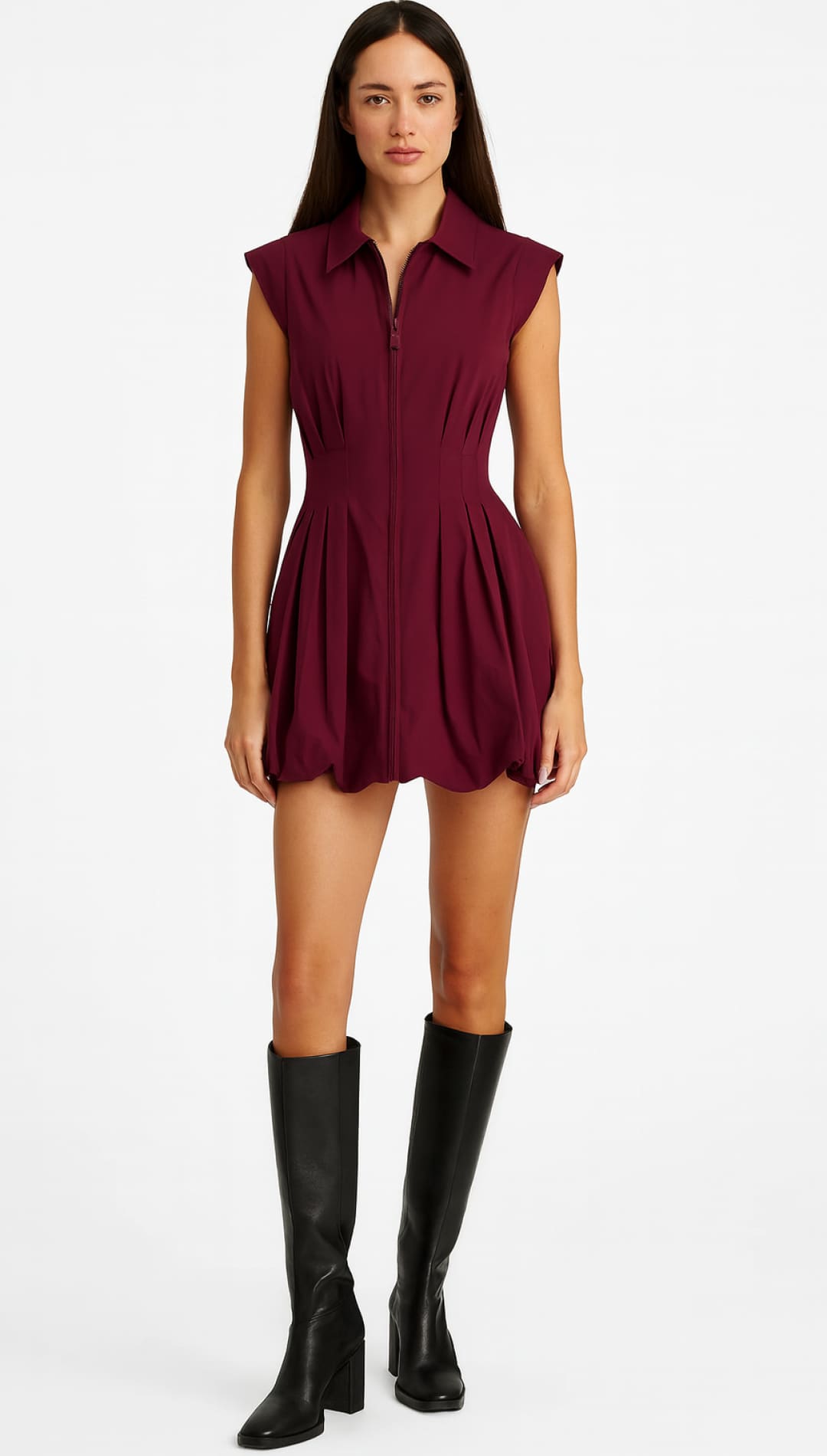 A woman wearing a burgundy collared romper with a front zipper and black knee-high boots.