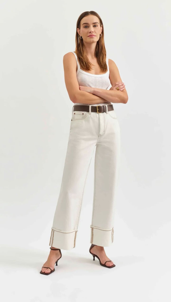 White wide-leg jeans with folded cuffs and a brown leather belt.