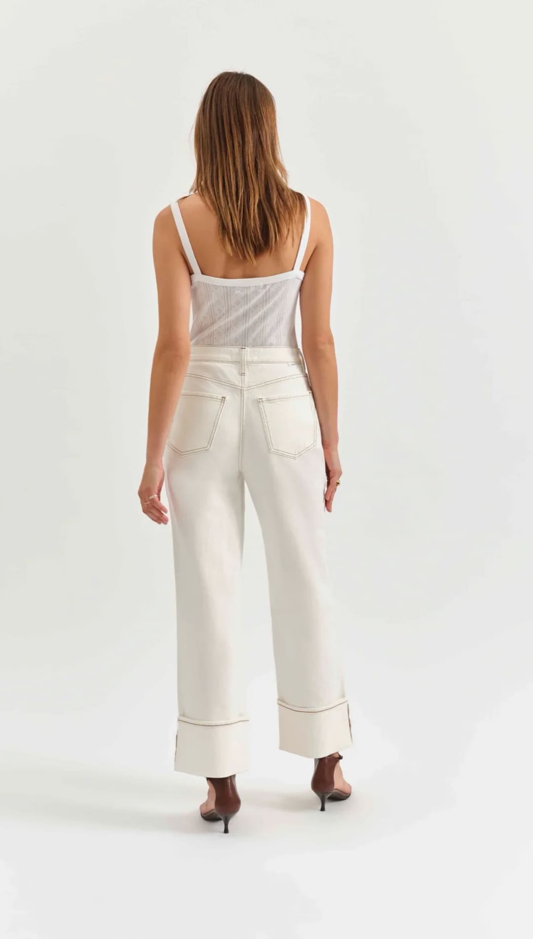 White wide-leg pants with rolled cuffs worn with a light-colored tank top.