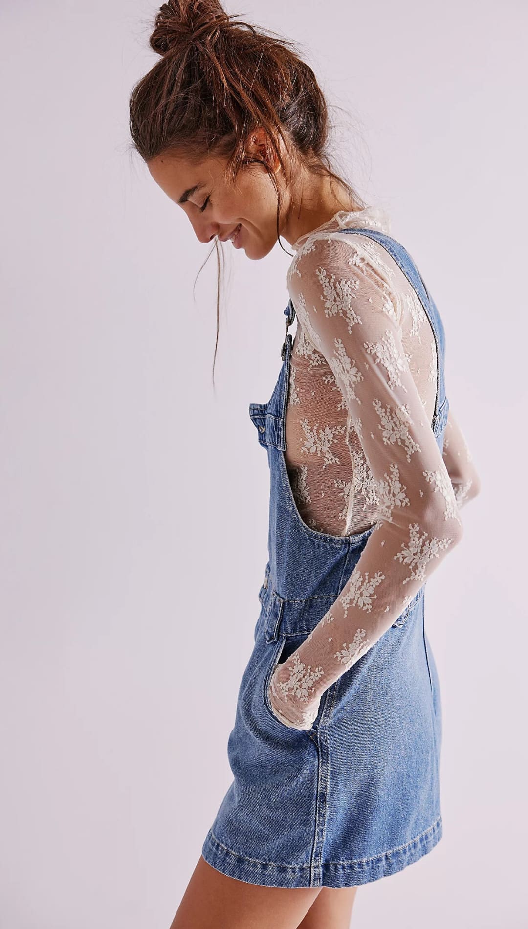 Denim overall dress with lace sleeves and a high ponytail hairstyle.