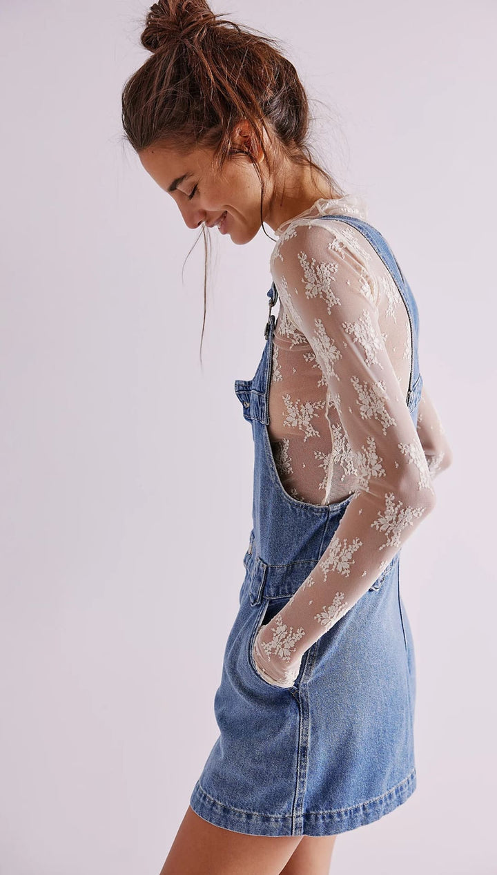 Denim overall dress with lace sleeves and a high ponytail hairstyle.