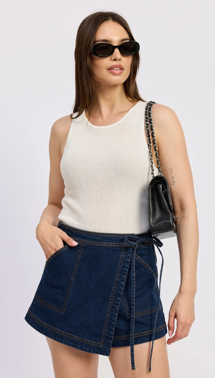 Woman in a ribbed tank top and denim wrap skirt.