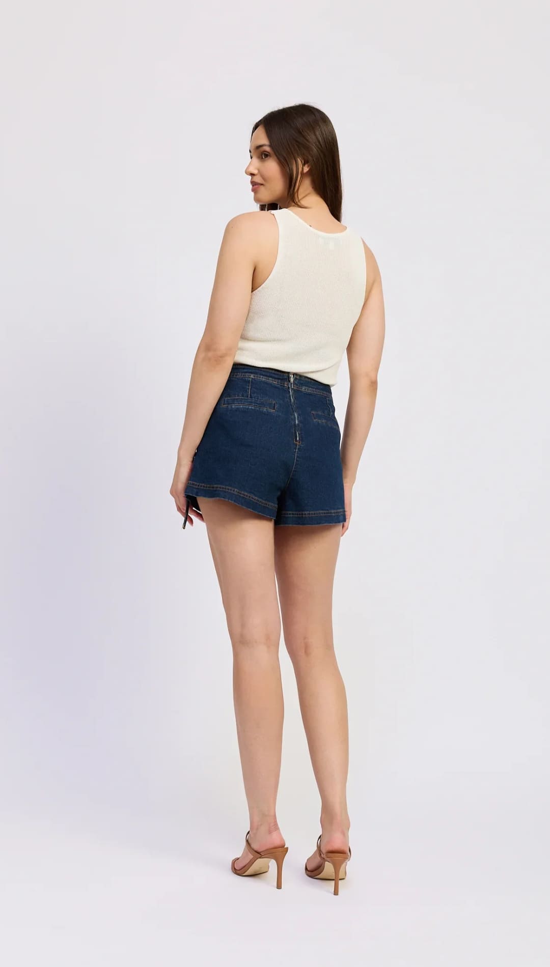 Woman wearing a tank top and denim shorts.