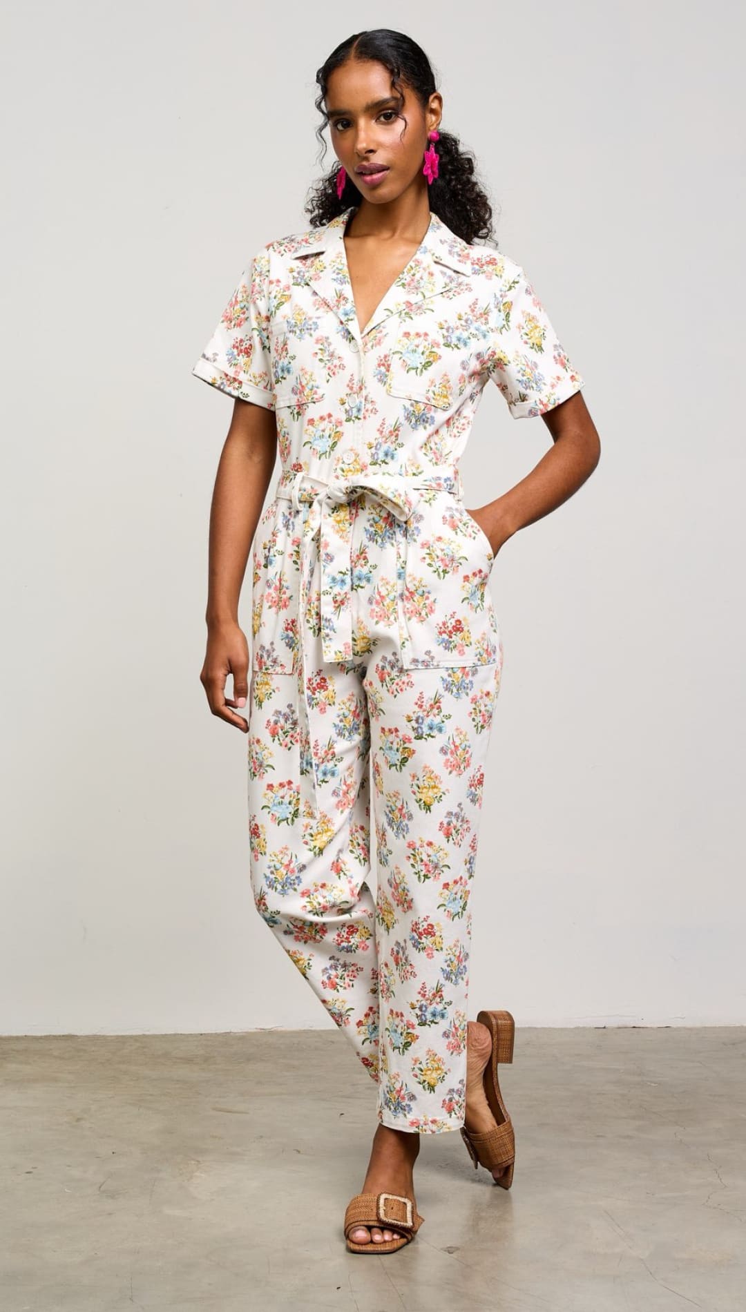 Floral print jumpsuit with short sleeves, collar, and tie waist detail.