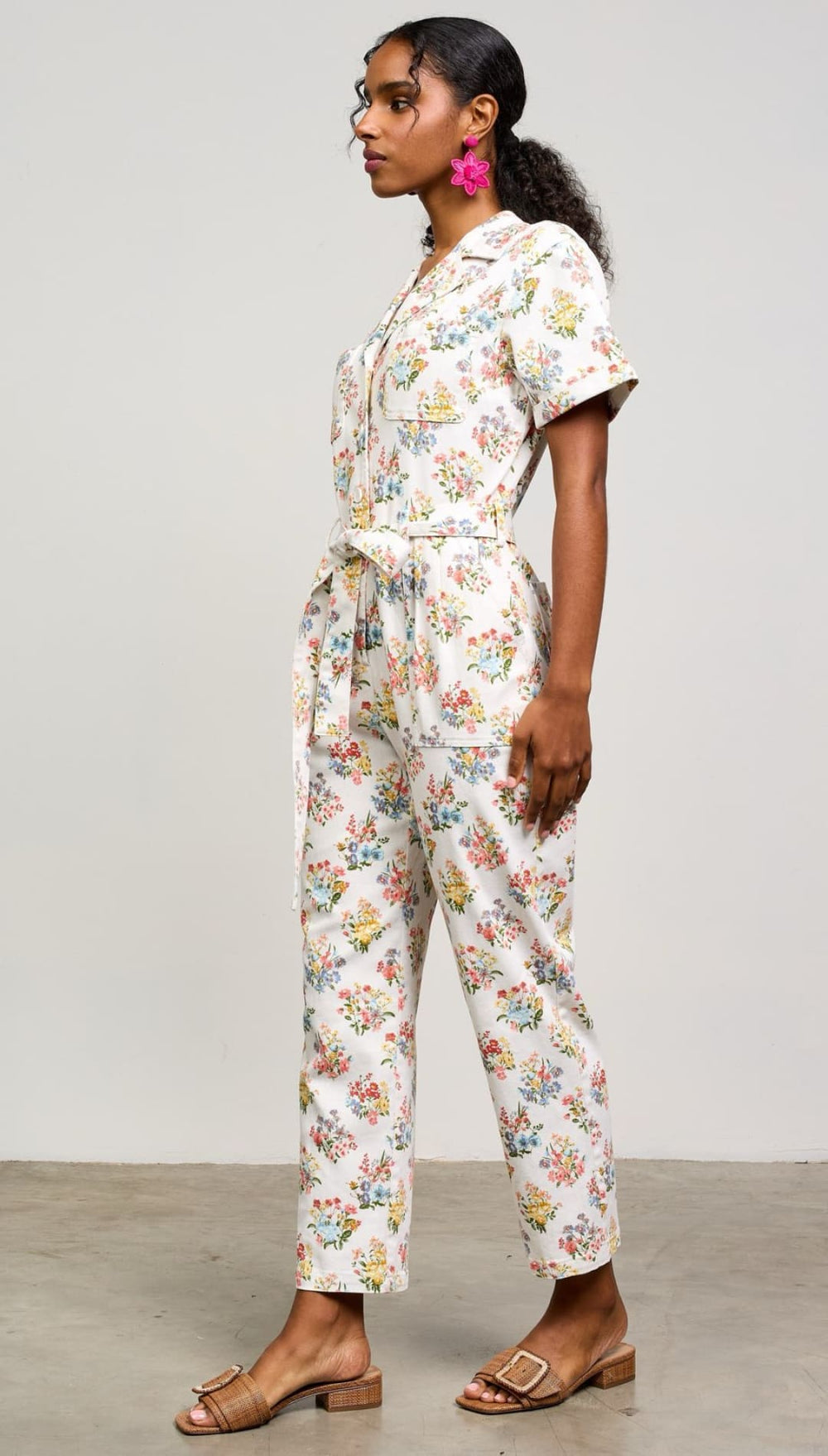 Floral print jumpsuit with short sleeves, collar, and tie waist detail.