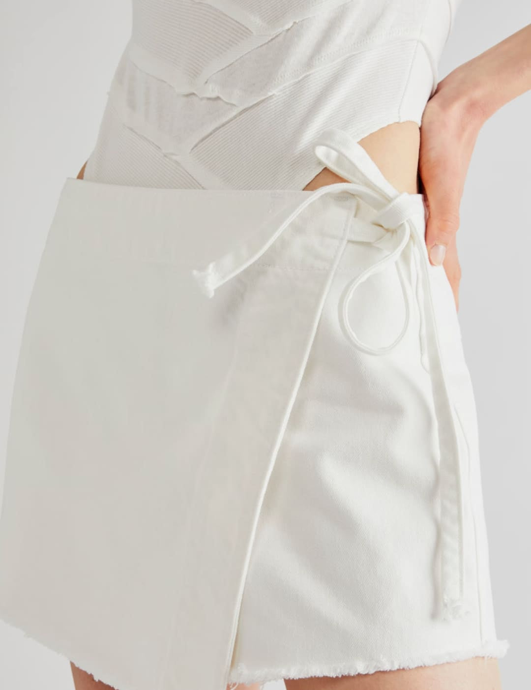 White wrap-style mini skirt with a frayed hem and matching drawstring tie.
