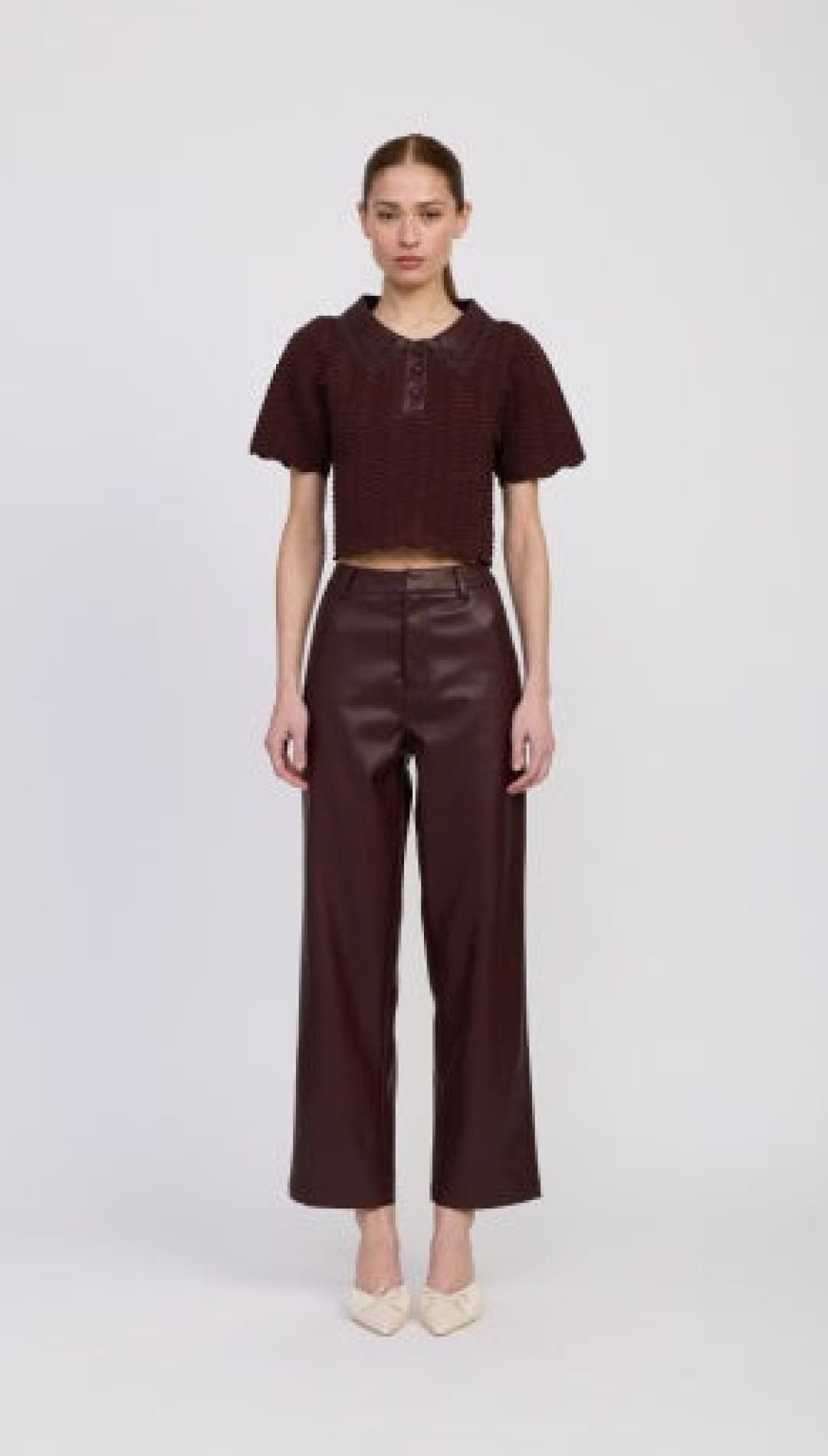 A short-sleeved, collared brown crop top with a button placket and puffed sleeves.