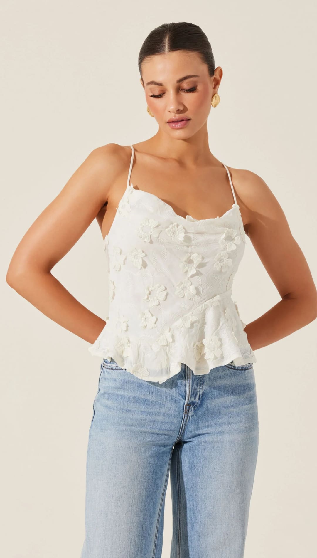 Woman in white floral camisole and jeans.