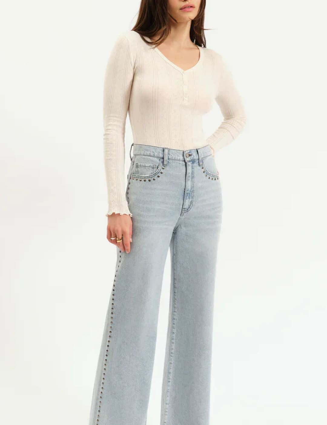 Woman wearing light-wash, wide-leg jeans with studded accents.