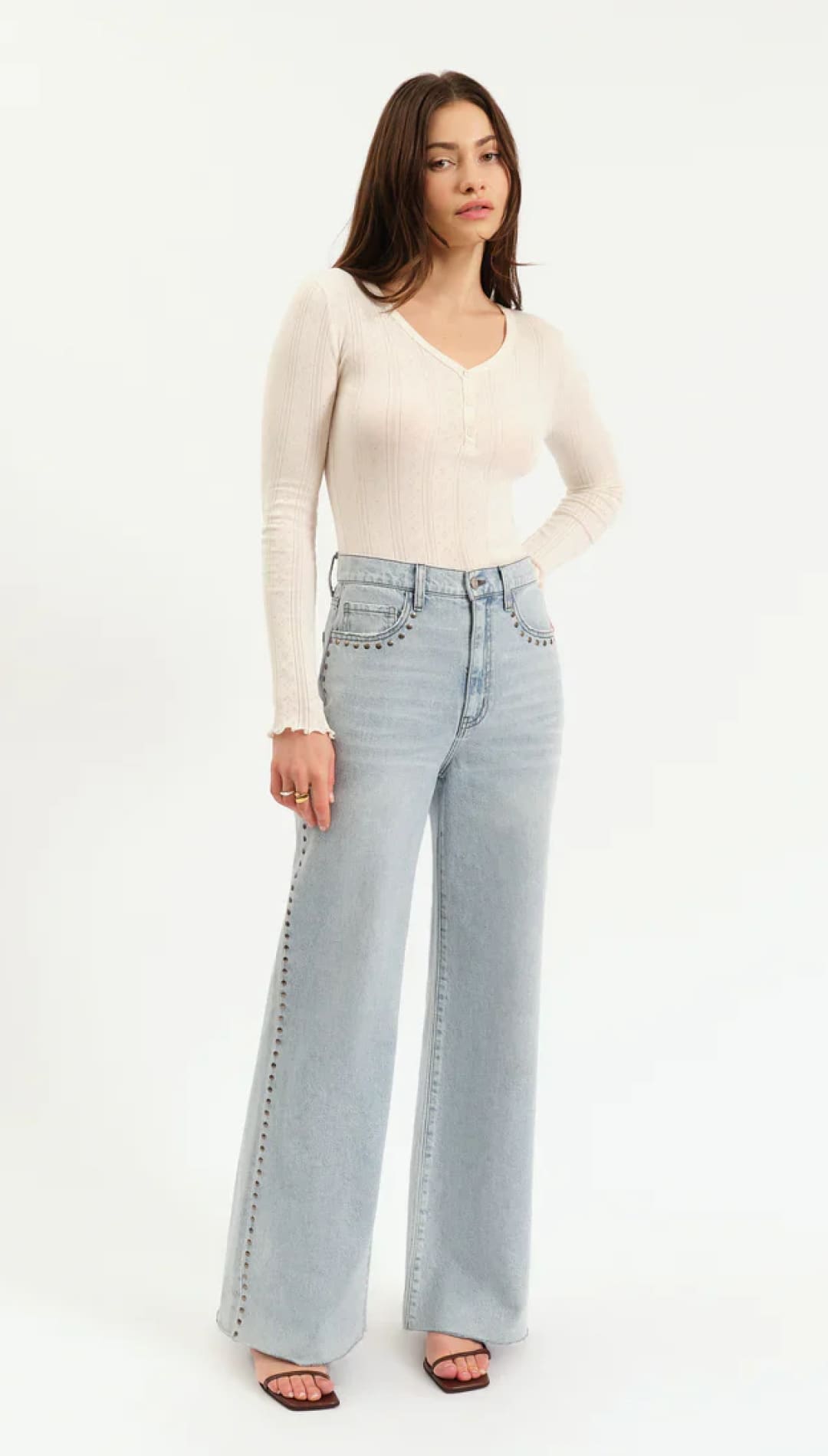 Woman wearing light-wash, wide-leg jeans with studded accents.