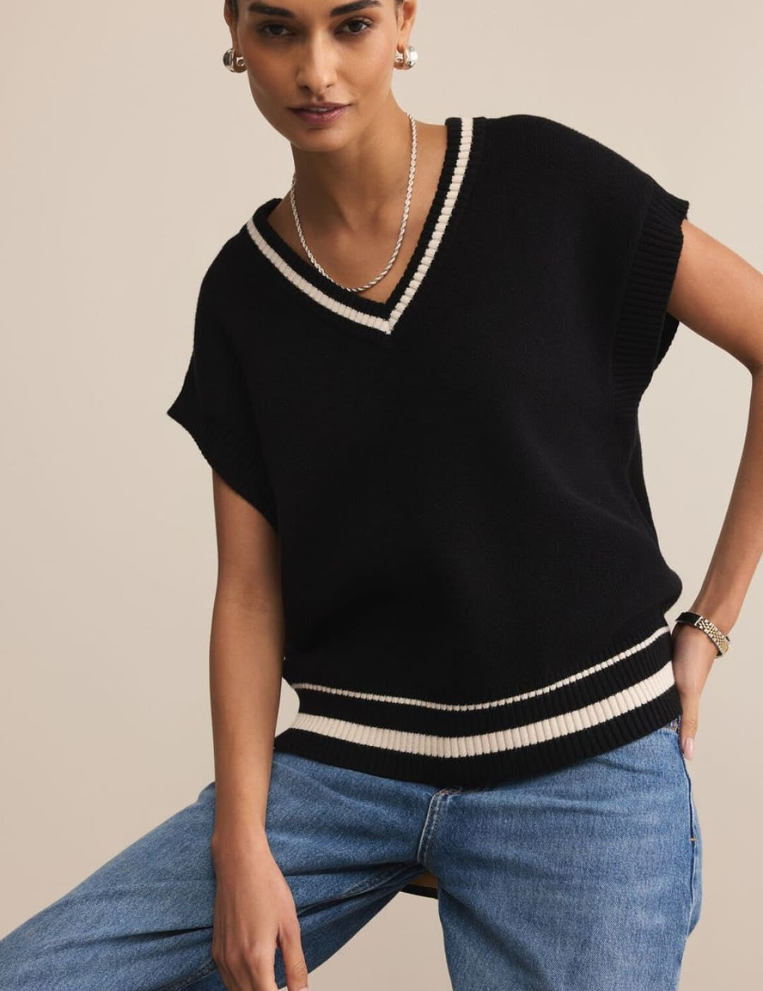 Black and white striped v-neck sweater with short sleeves, made of knit material.
