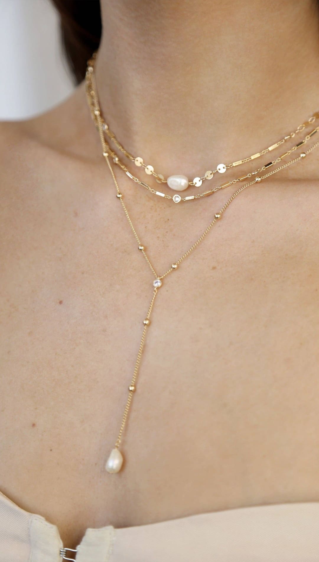 Layered gold necklaces with pearls.