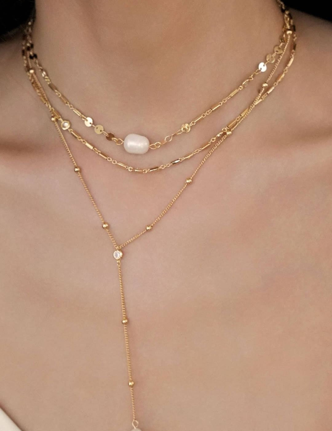 Layered gold necklaces with pearls.
