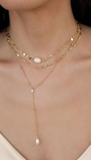 Layered gold necklaces with pearls.