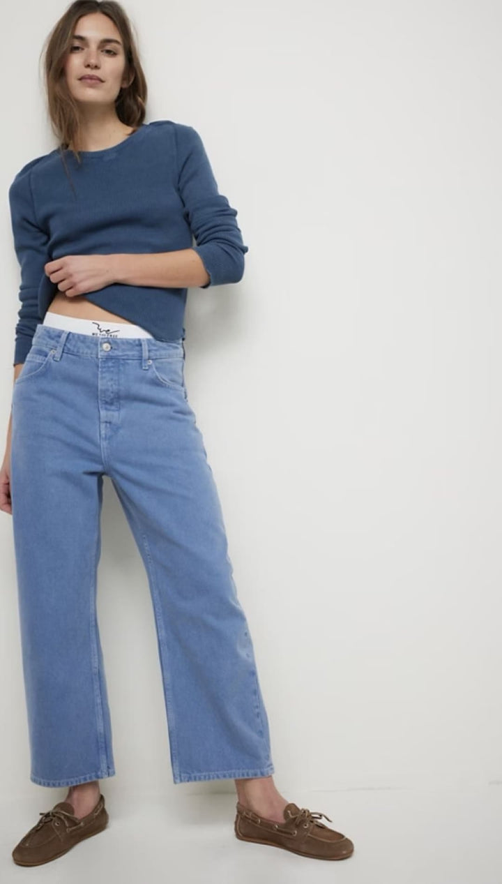 Woman wearing blue jeans and a blue long-sleeved shirt.