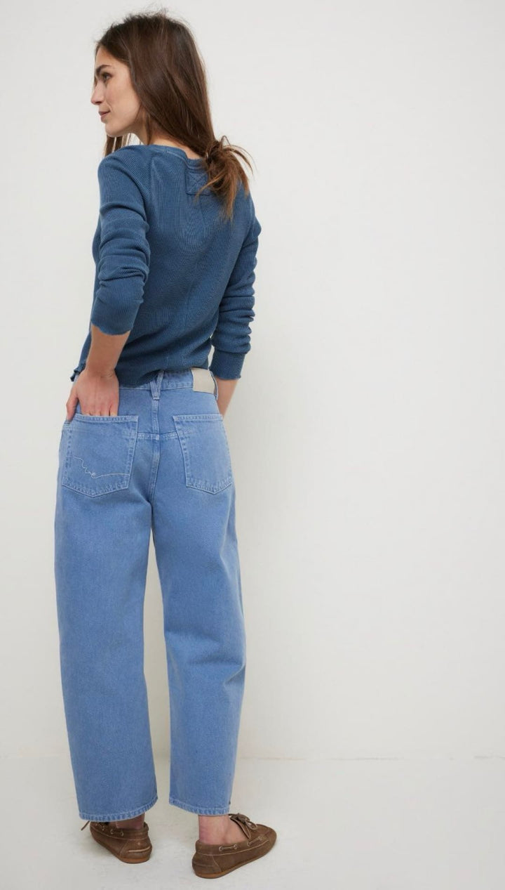 Woman in blue top and wide-leg jeans.