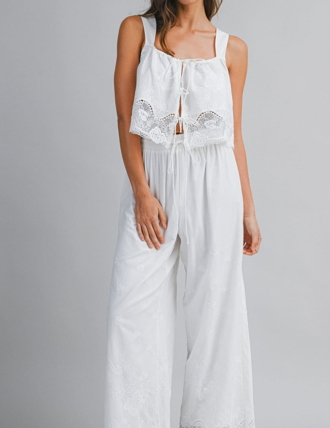 White lace-trimmed jumpsuit with a square neckline and wide-leg pants.