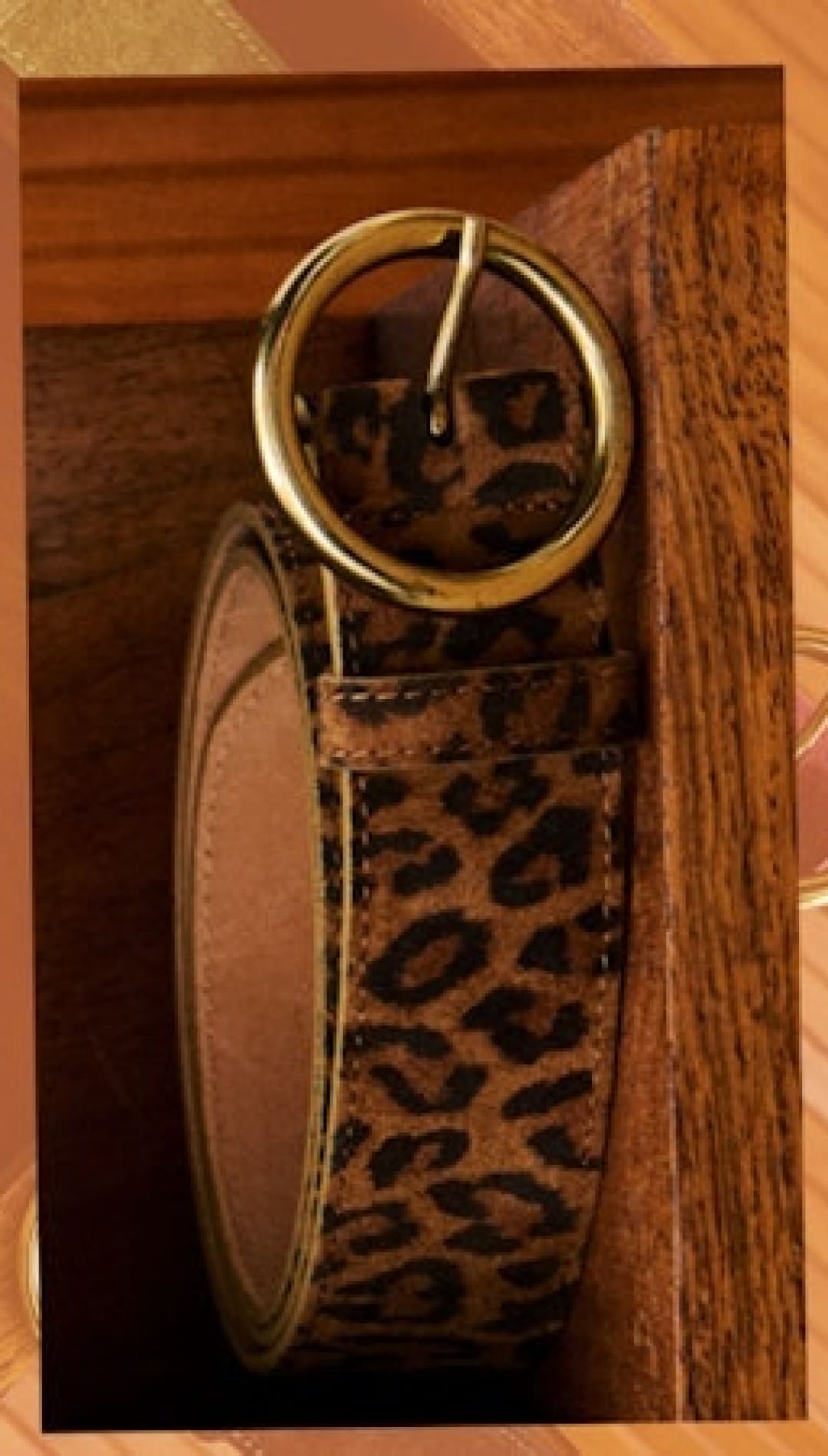 Leopard print belt with a round gold buckle.