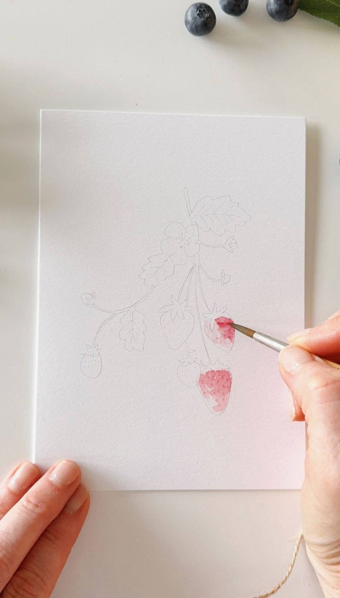 Watercolor brush pen with pink and red hues, wooden handle, transparent cap.