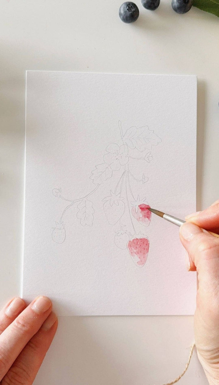 Watercolor brush pen with pink and red hues, wooden handle, transparent cap.